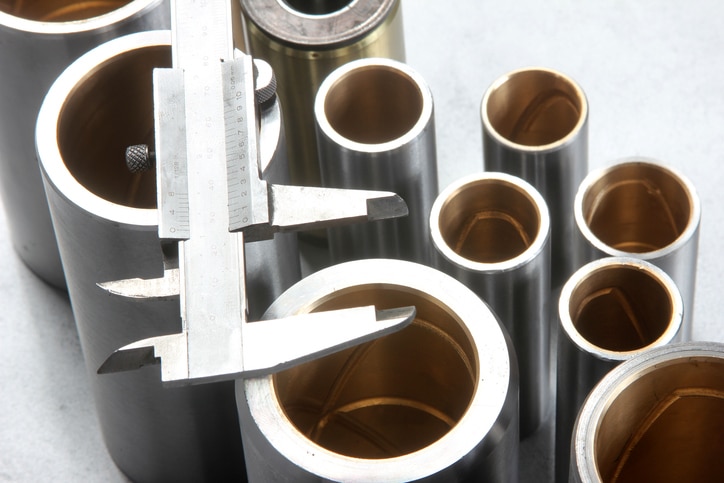 Precision measurement of industrial roller components using a caliper during quality inspection.